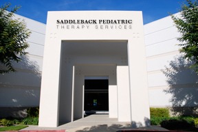 A white building with the words saddleback pediatric therapy services on it.