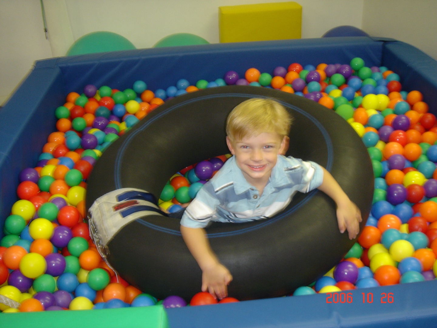 A boy in a pool of balls with an inner tube.