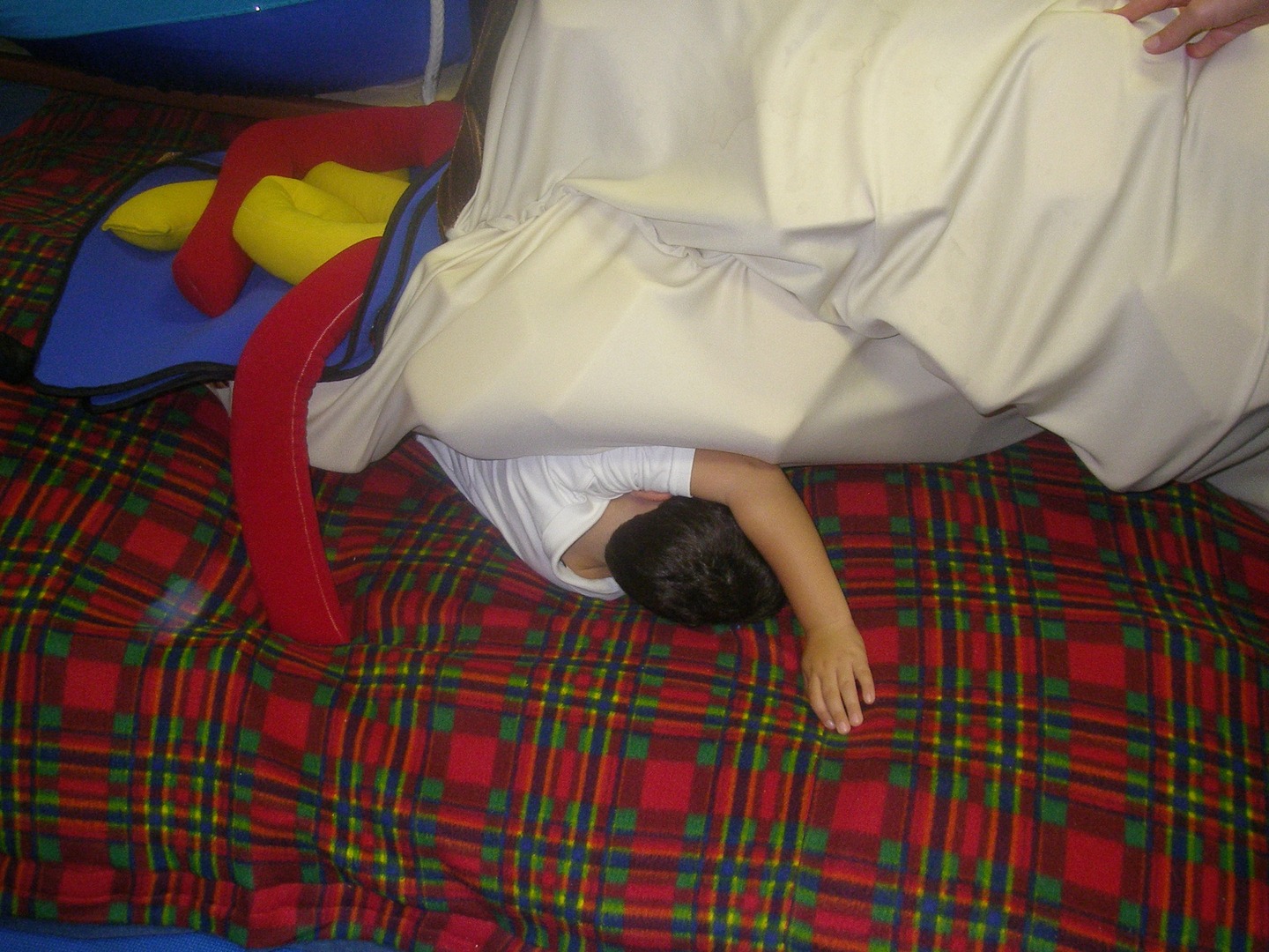 A child is laying on the bed under sheets.