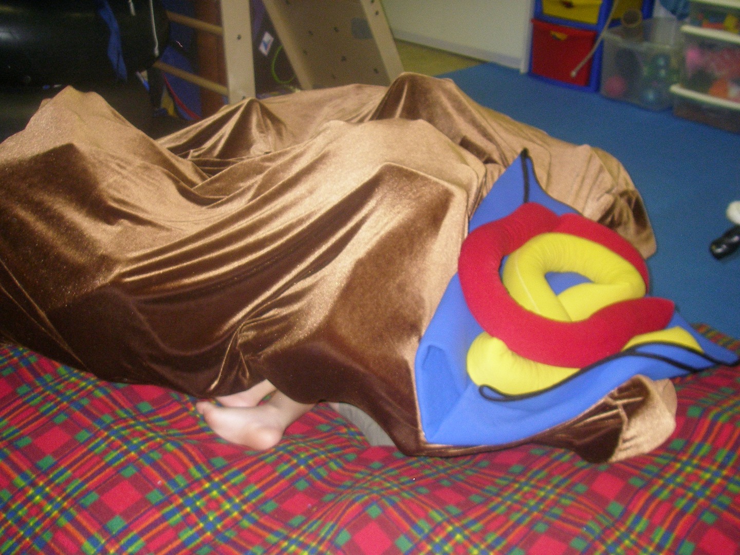 A brown blanket with a superman pillow on it
