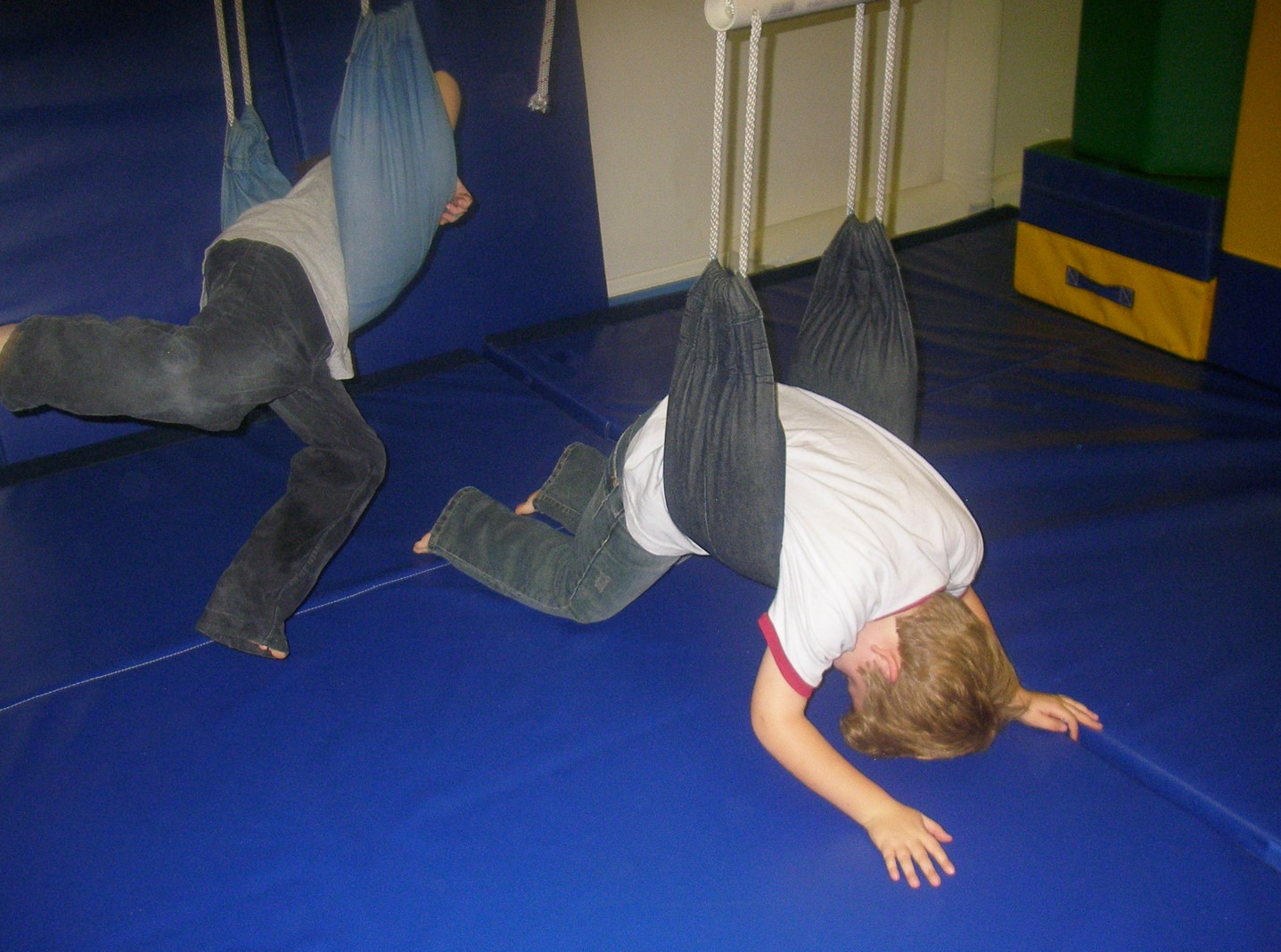 Two children are playing on a blue mat.