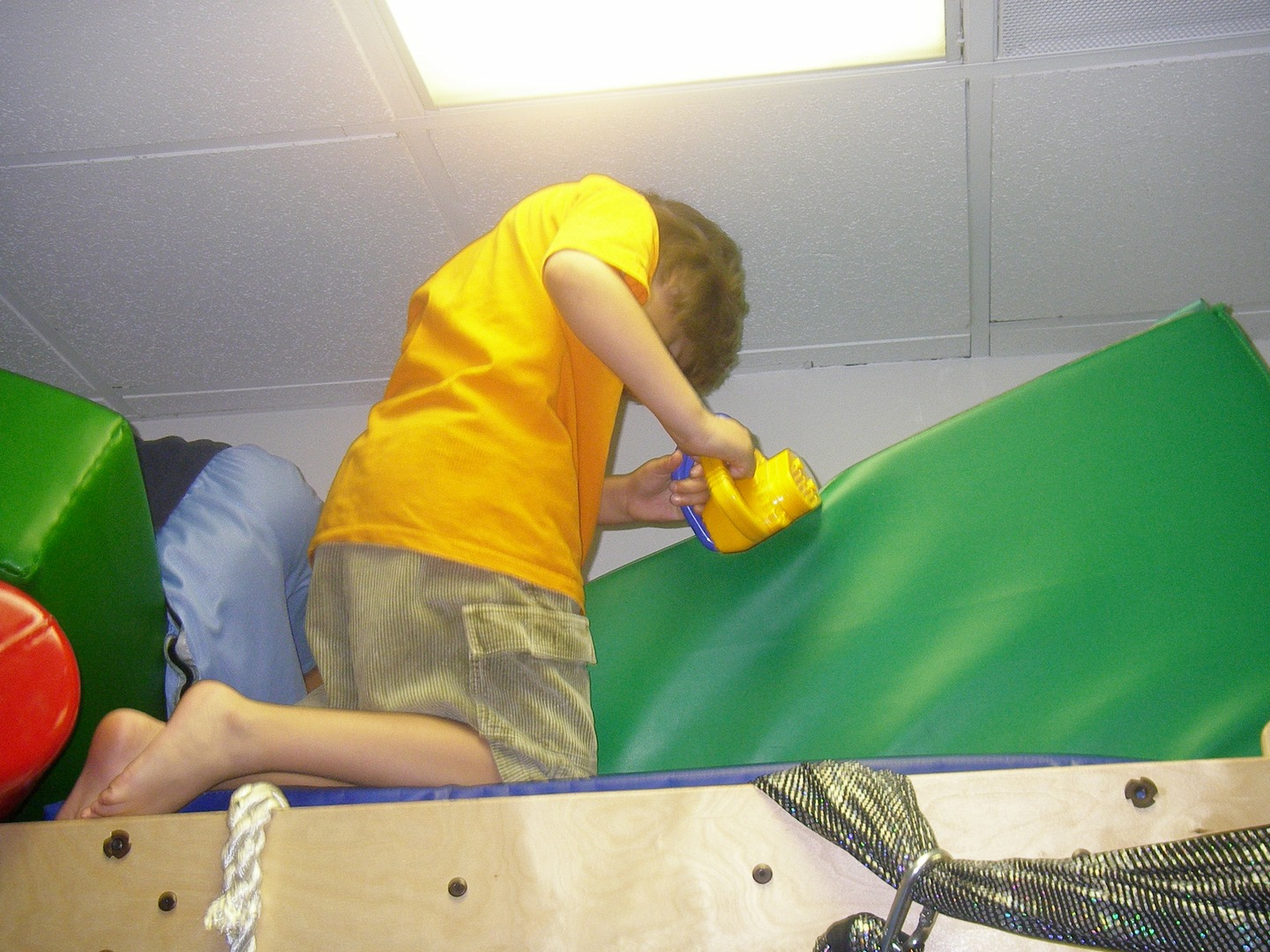 A boy is cleaning the wall on a climbing wall.
