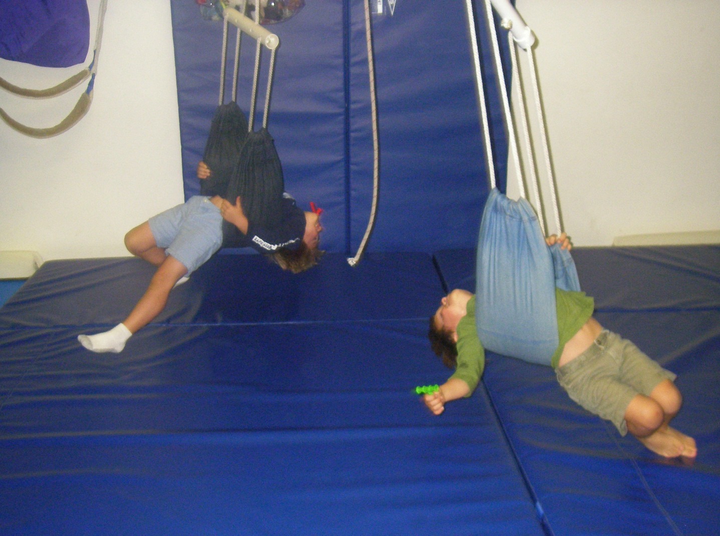 Two people hanging from a rope on a blue wall.