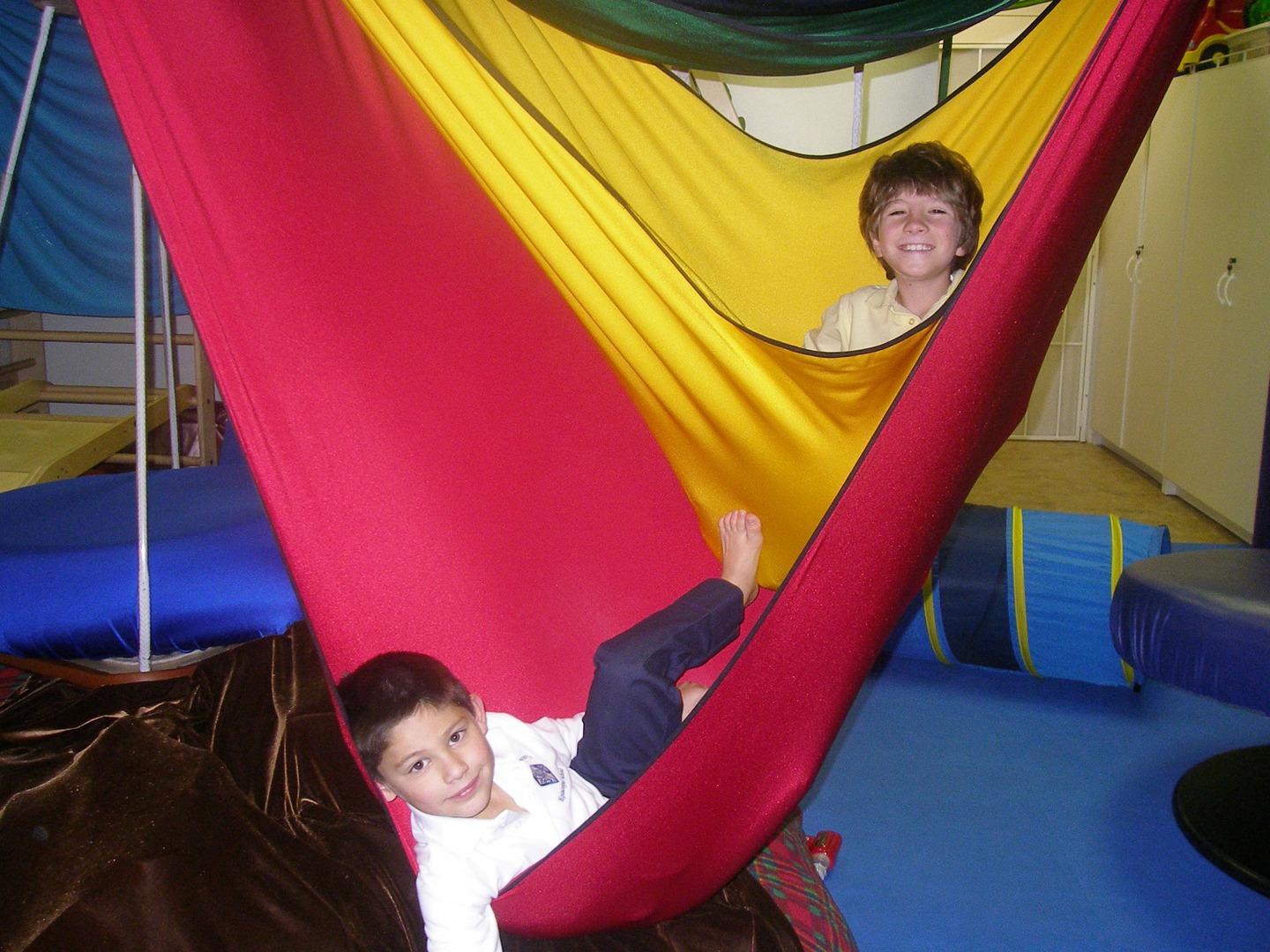 Two children are playing on a hammock.