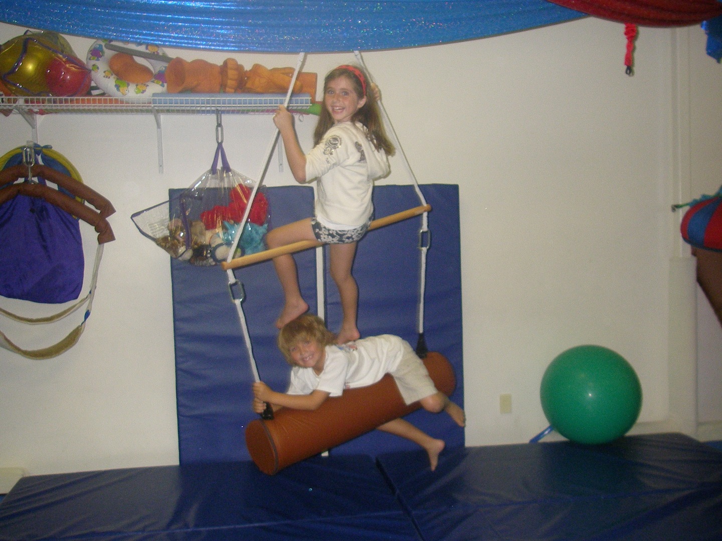 Two children playing on a swing set in the room.