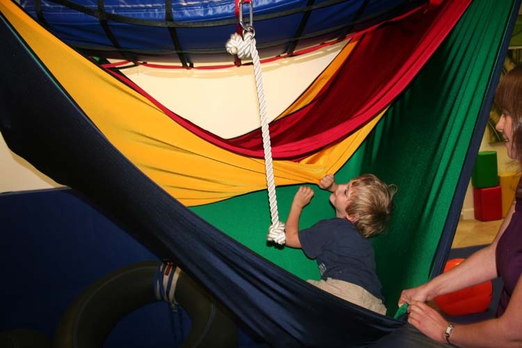 A child is hanging in a hammock with a colorful canopy.