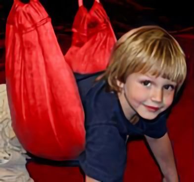 A young child is playing with a red bag.